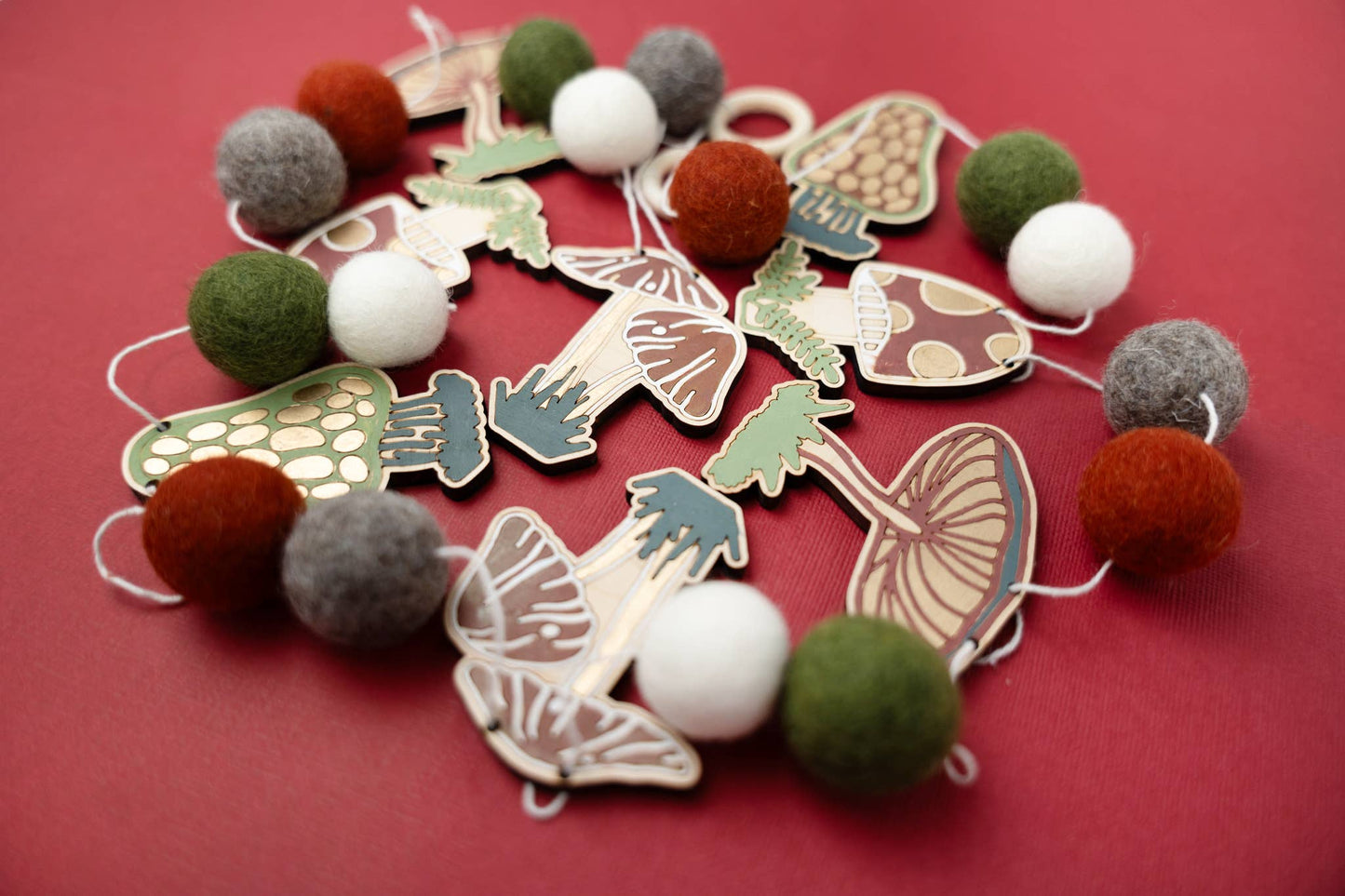Garland of felt balls and wooden mushroom shapes on a red background