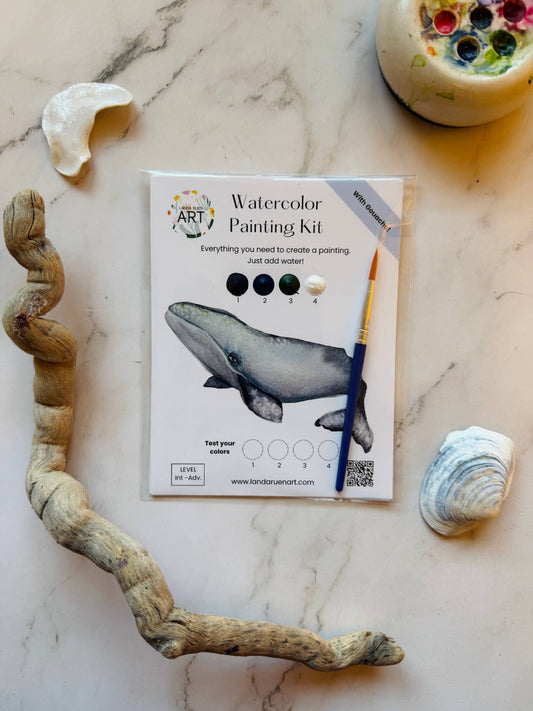Watercolor painting kit with whale illustration on a marble surface with natural elements.