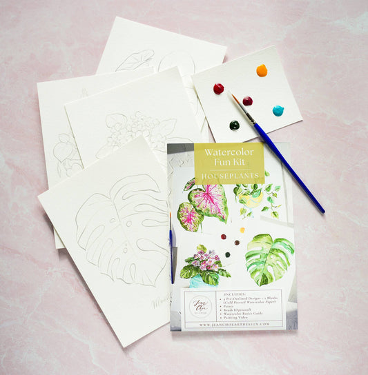 Watercolor fun kit with houseplants, paper, and paintbrush on a pink background