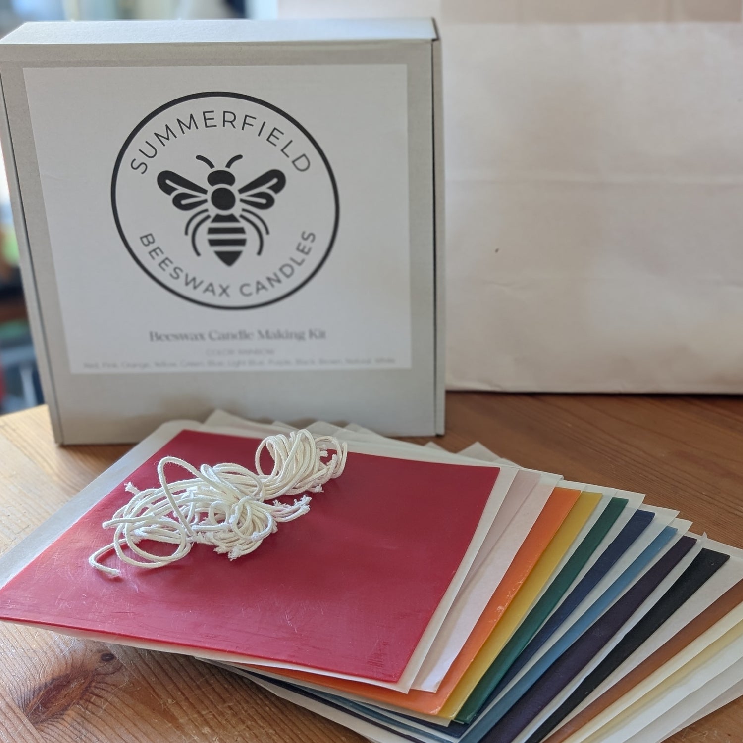 Summerfield Beeswax Candles candle-making kit with a bundle of wicks and a rainbow of beeswax sheets on a wooden surface.