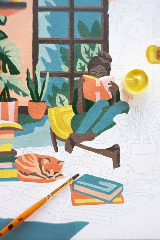 Painting of a person reading a book in a cozy room with plants, books, and a cat.