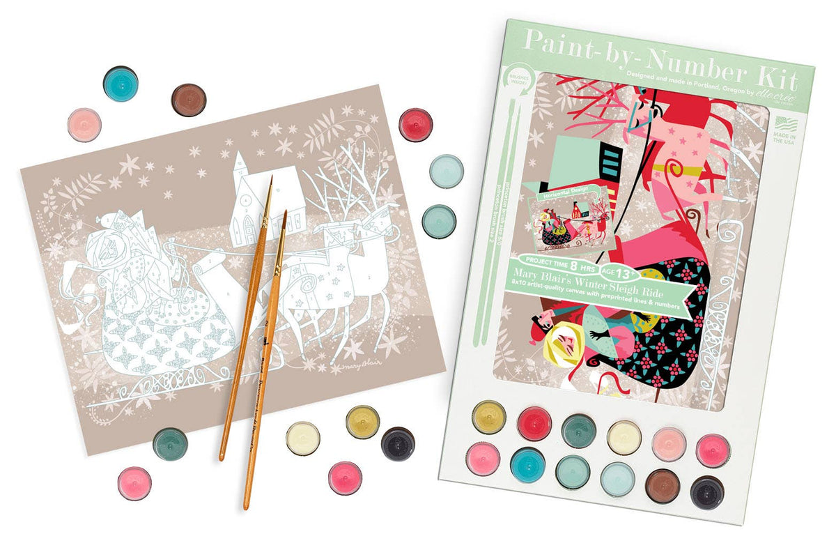 A Christmas-themed paint-by-number kit shown with its illustrated cover, a partially completed number sheet, two paintbrushes, and multiple round paint pans arranged on a white background.