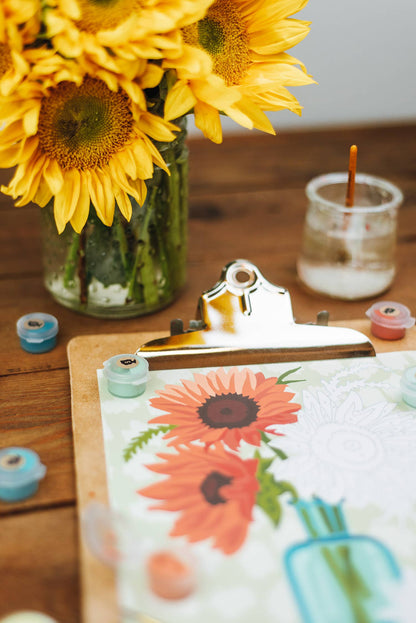Sunflower painting on a wooden table with sunflowers in the background