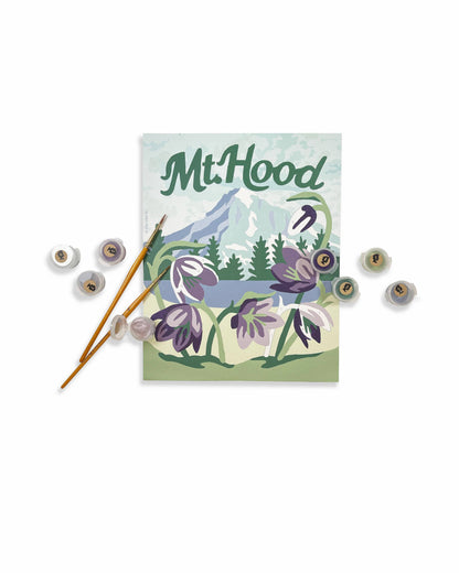 Finished Paint by number kit with Mt. Hood design, flowers, and mountain on a white background. Paintbrushes and paint pods in the foreground.