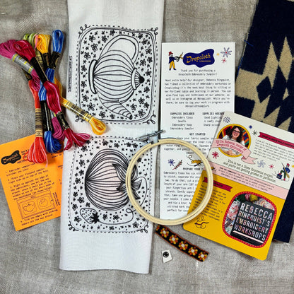 Embroidery kit with patterns, thread, hoop, and instructions on a textured surface