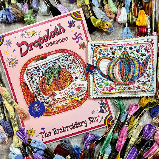 Embroidery kit with colorful threads and a completed embroidery project on a table.