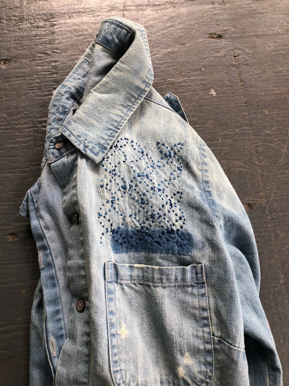 Denim jacket with a finished embroidery overlapping circle pattern on a wooden surface