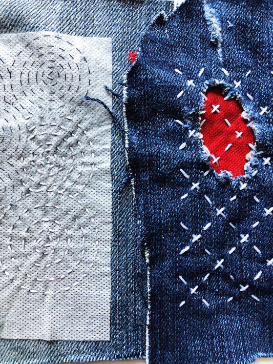 Close-up of denim fabric with an in-progress sashikio patch and textured gray fabric.