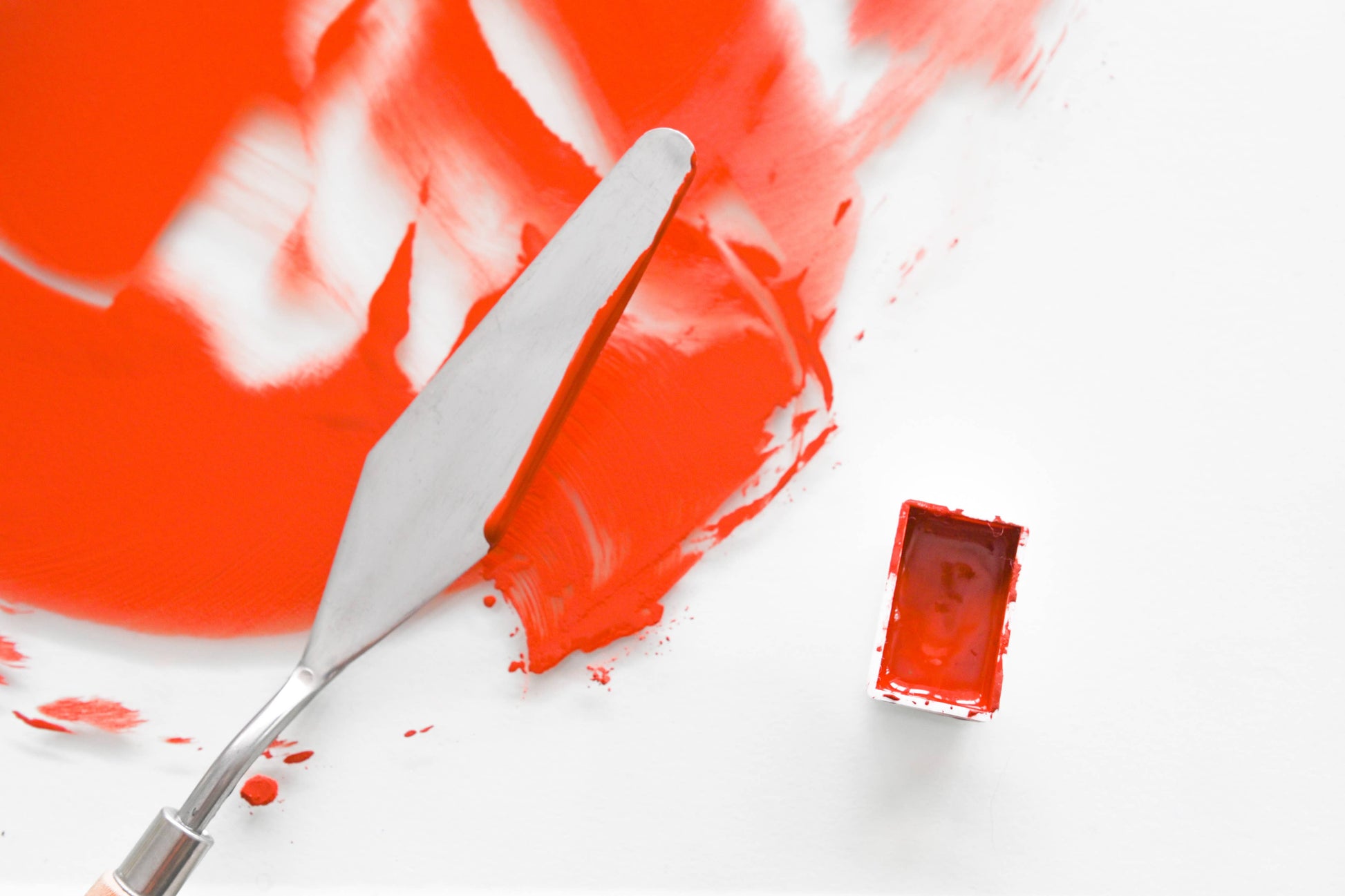 Red watercolor paint with a palette knife on a white background