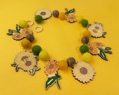 Garland of felt balls, wooden sunflower shapes on a yellow background