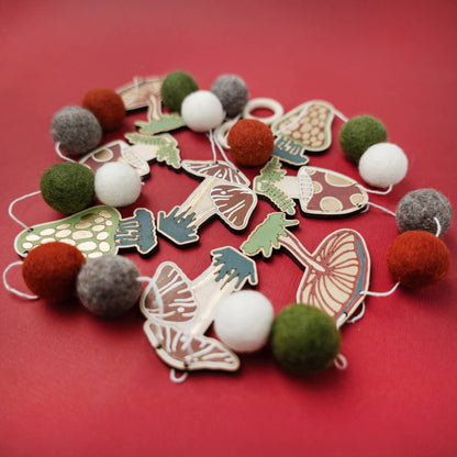 Garland of felt balls and wooden mushroom shapes on a red background