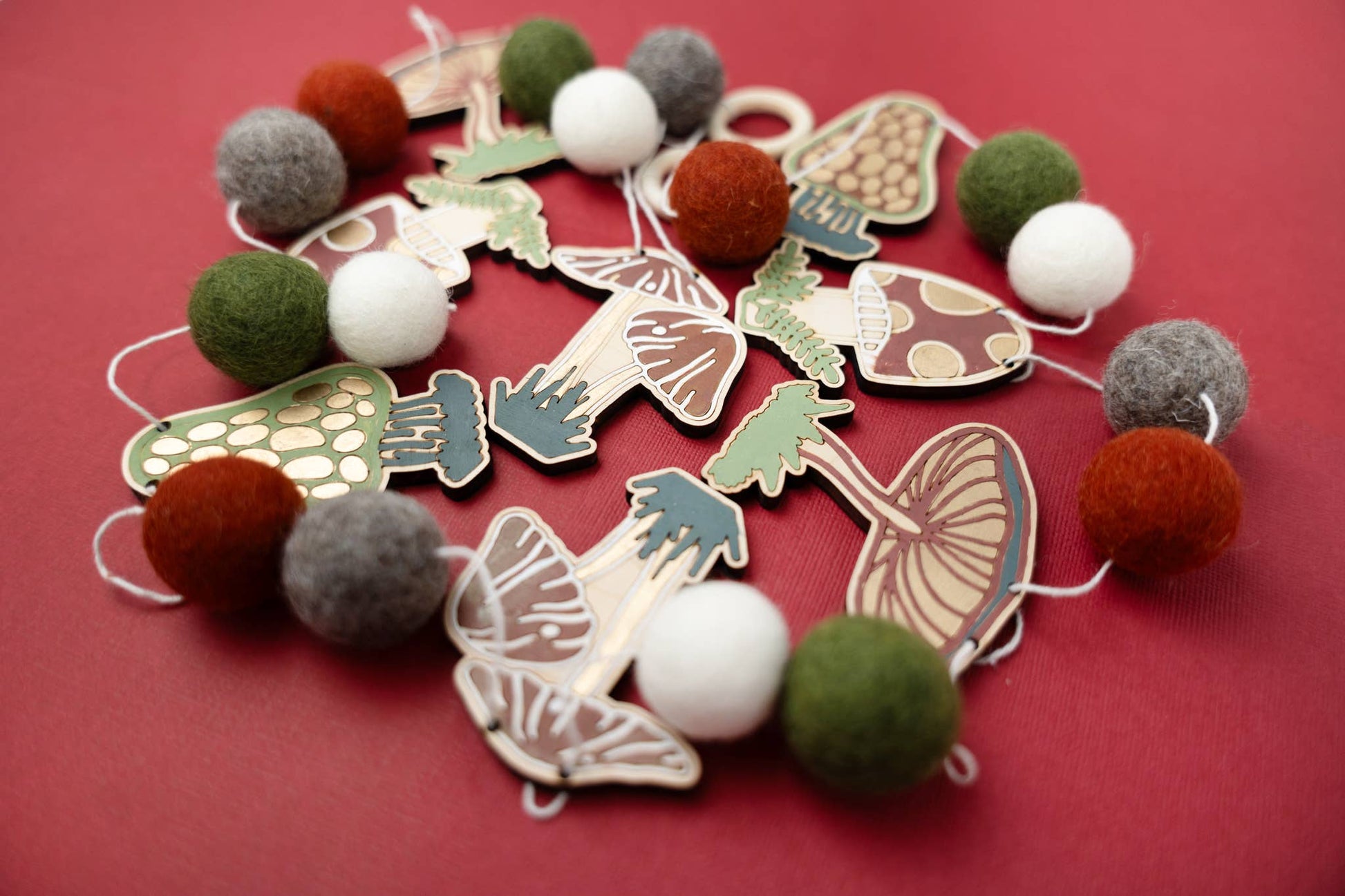 Garland of felt balls and wooden mushroom shapes on a red background