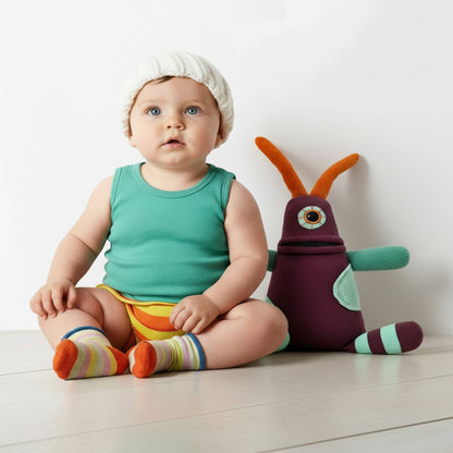 Baby sitting on a white floor with a colorful toy next to them