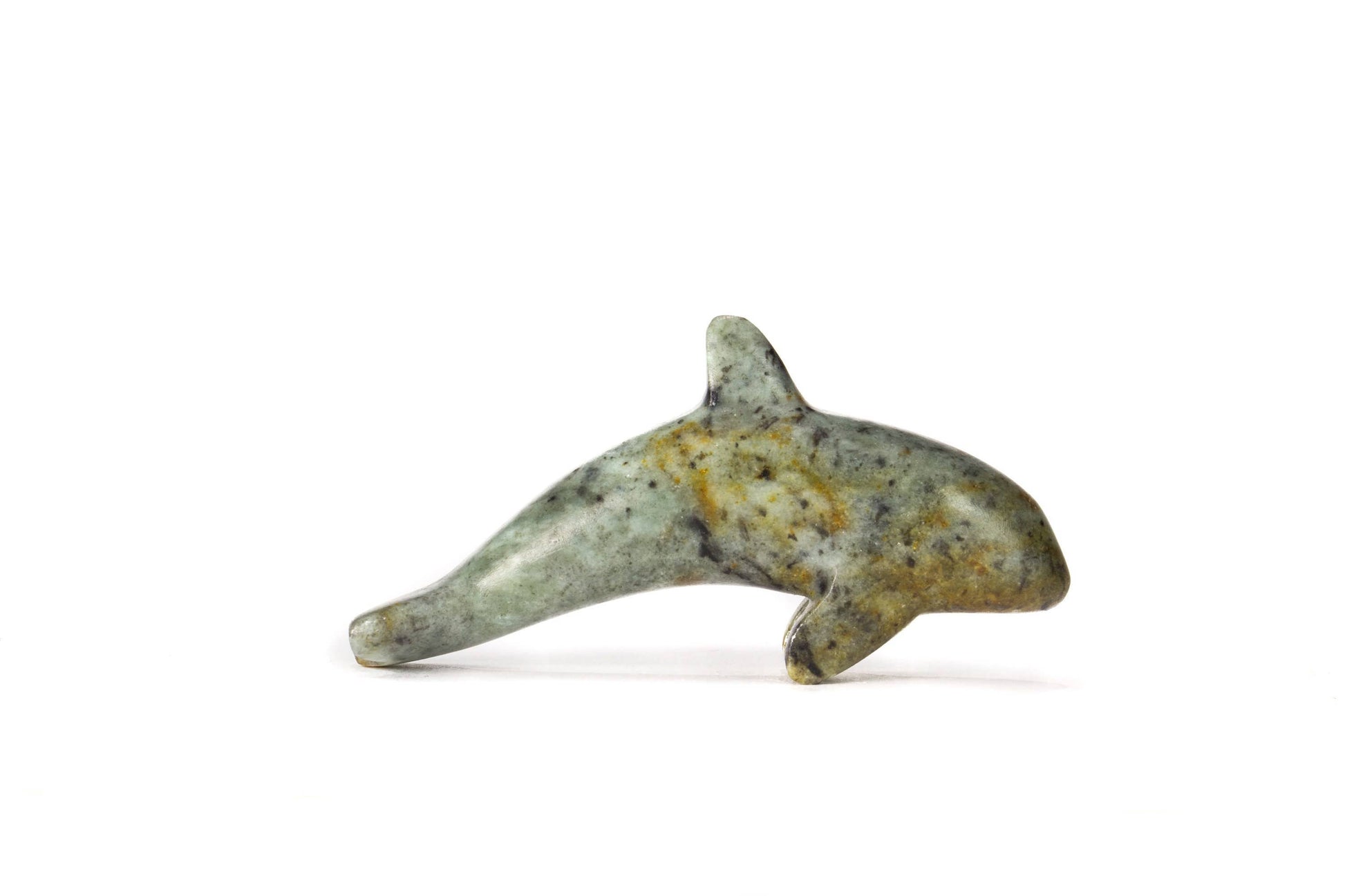 A finished soap stone carving of an orca figurine on a white background