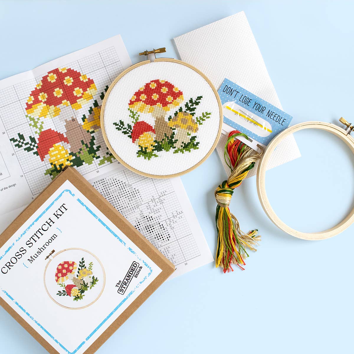 A similar kit with a different mushroom design  contents displayed on a pale blue background along with an example of the finished project. 