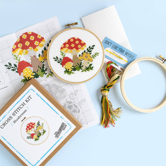 A similar kit with a different mushroom design  contents displayed on a pale blue background along with an example of the finished project. 